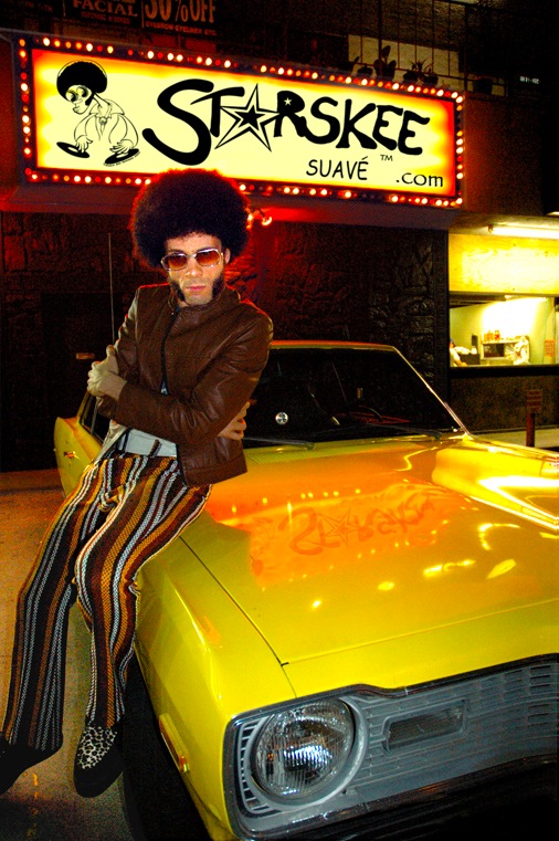 funky male human in bell bottoms, sitting on edge of a yellow, 1973 Dodge Dart Swinger, his name in lights behind